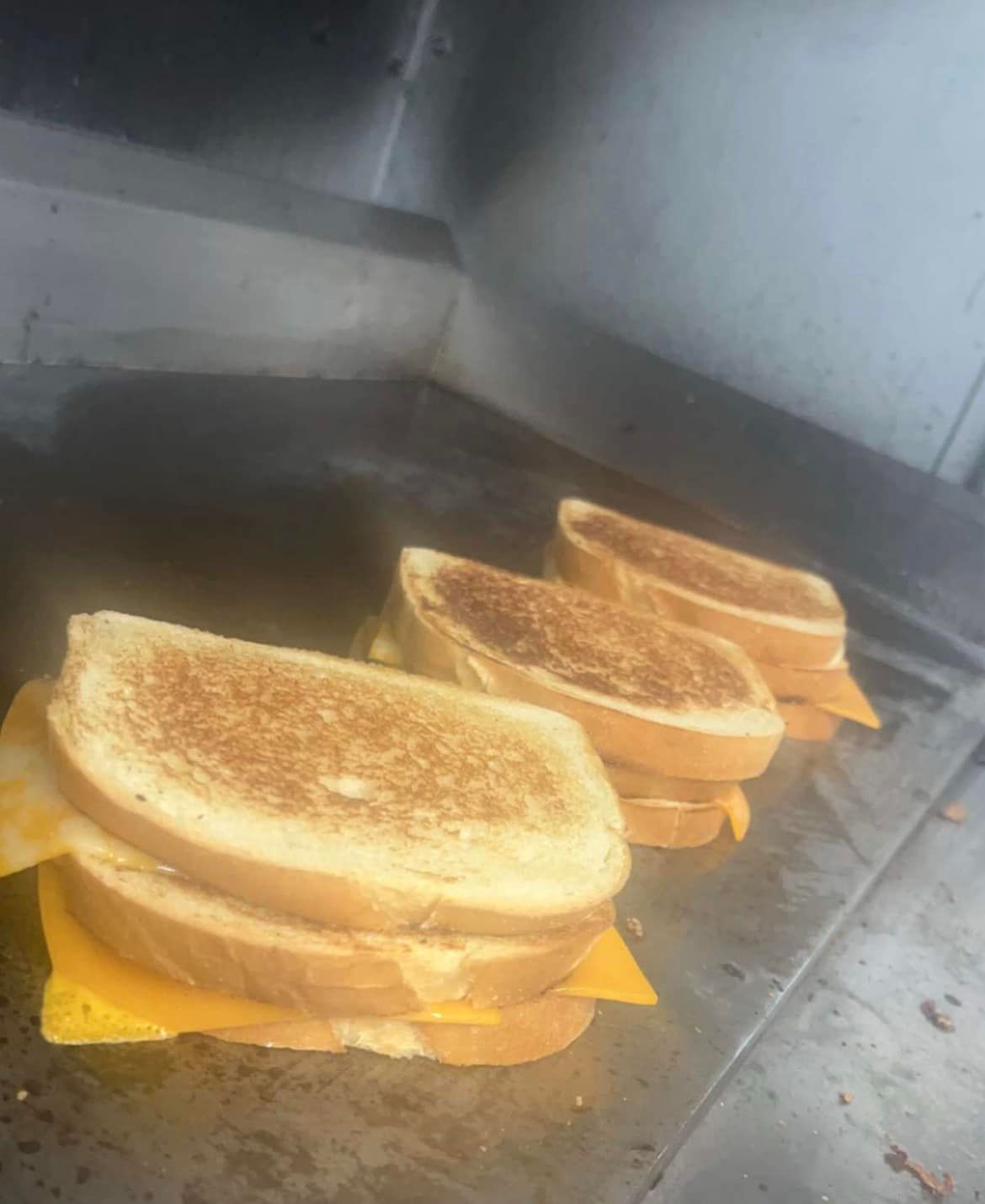 three grilled cheese sandwiches are being cooked on a grill .