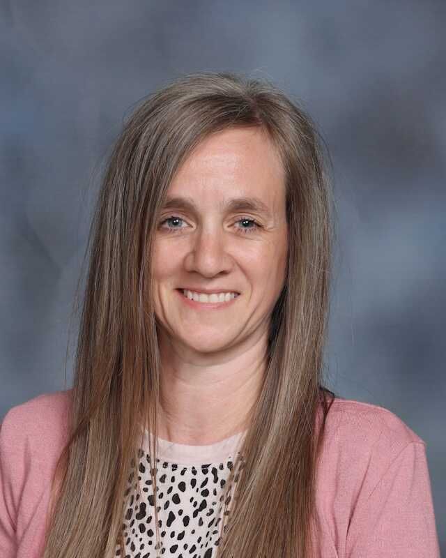 A woman with long hair is wearing a pink sweater and a leopard print shirt.
