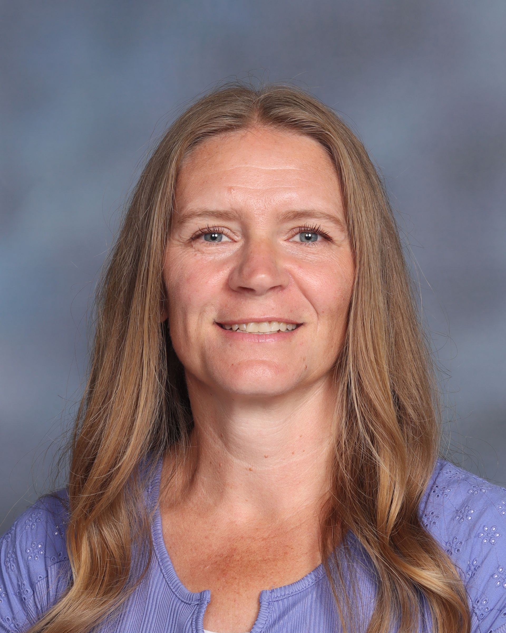 A woman with long blonde hair is smiling for a picture.