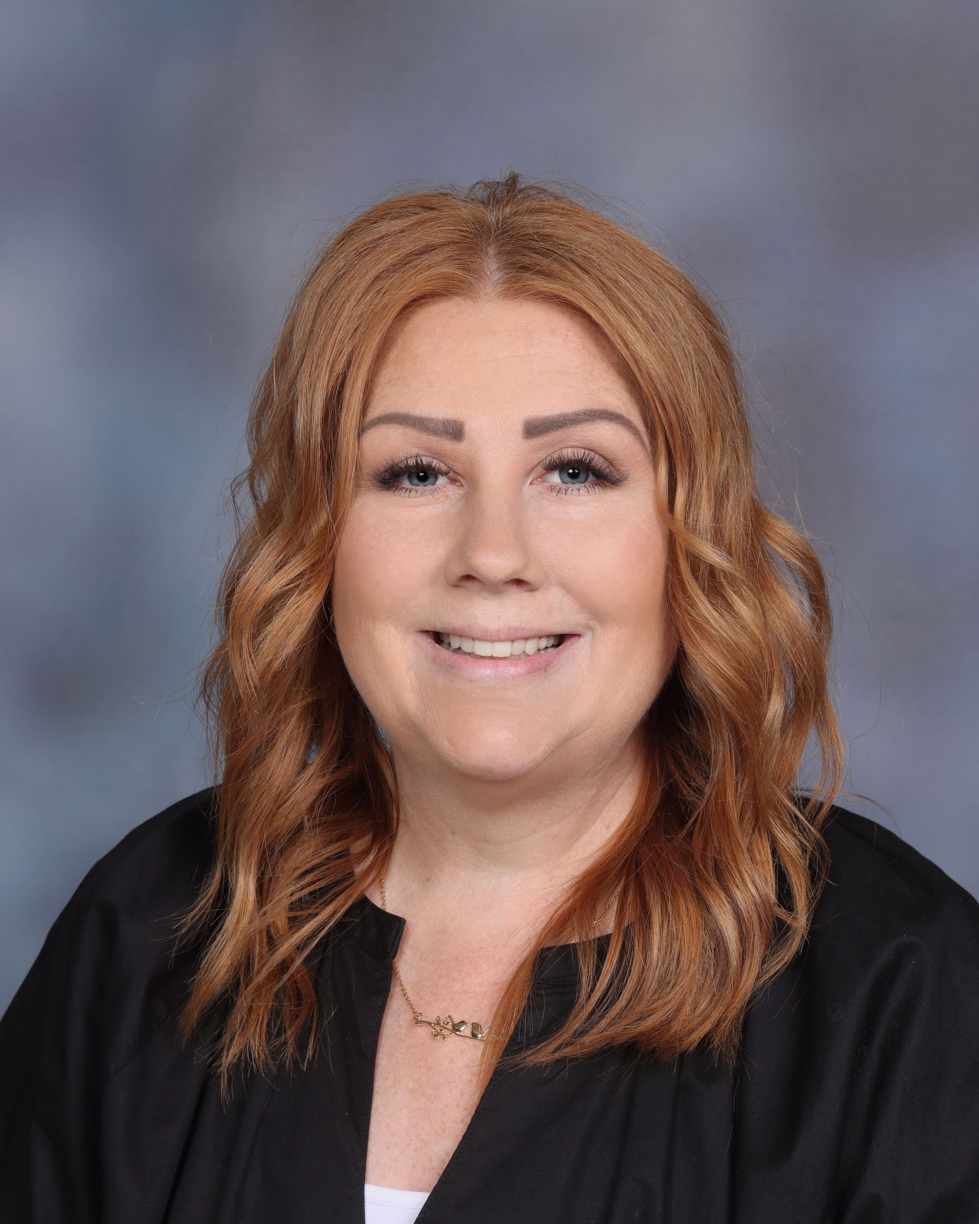 A woman with red hair and a green sweater is smiling for a picture.