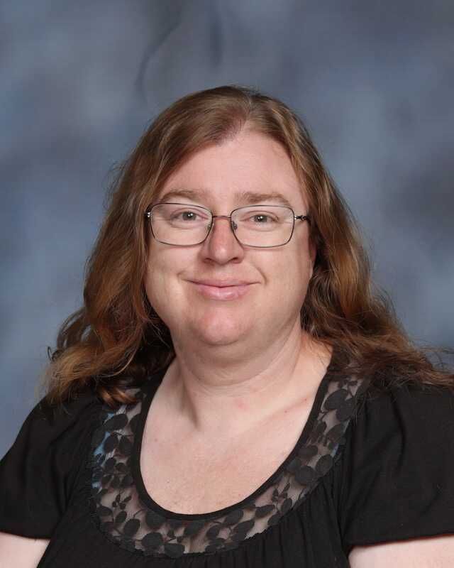 A woman wearing glasses and a black shirt is smiling for the camera.