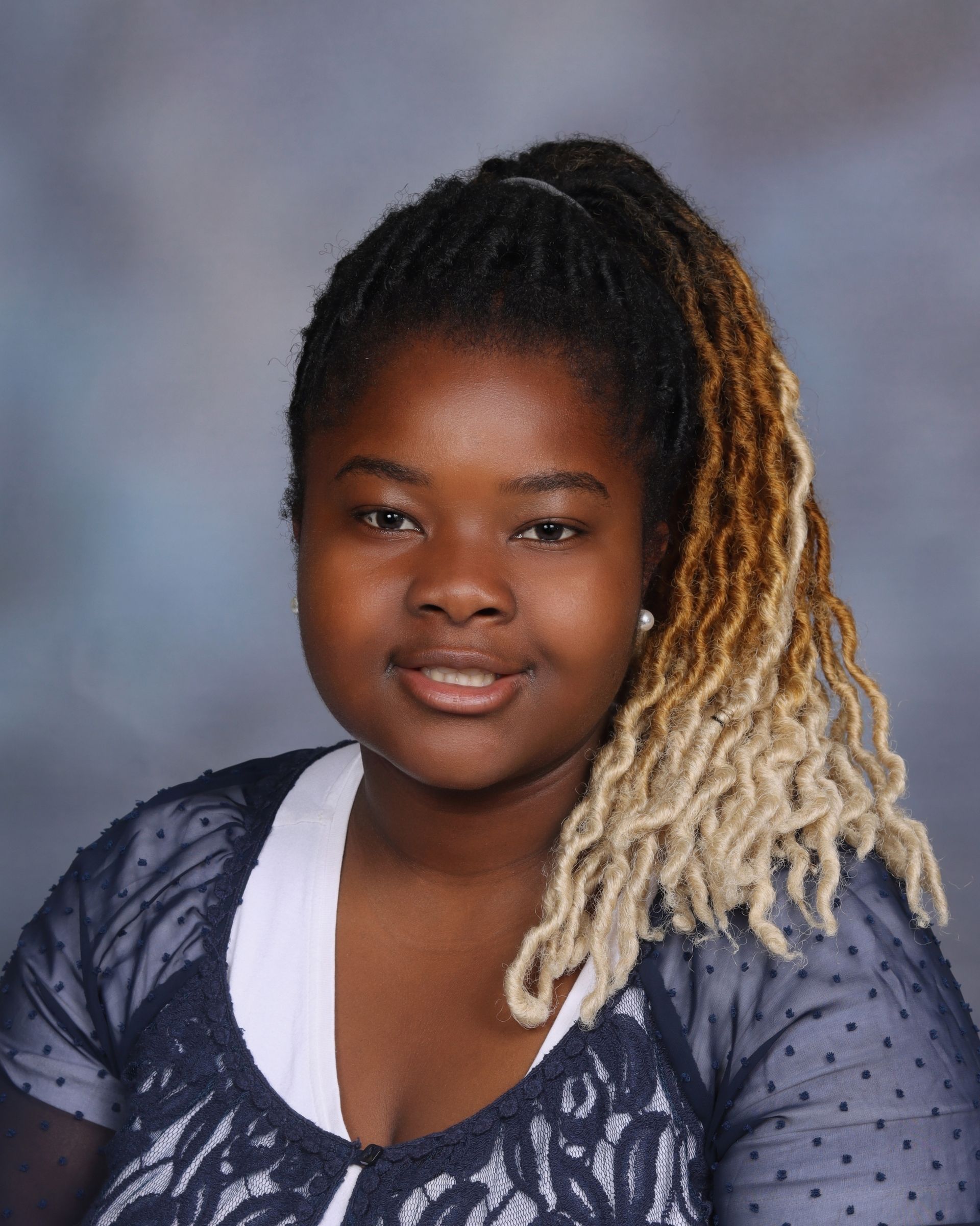 A young woman in a pink plaid shirt is smiling for the camera.
