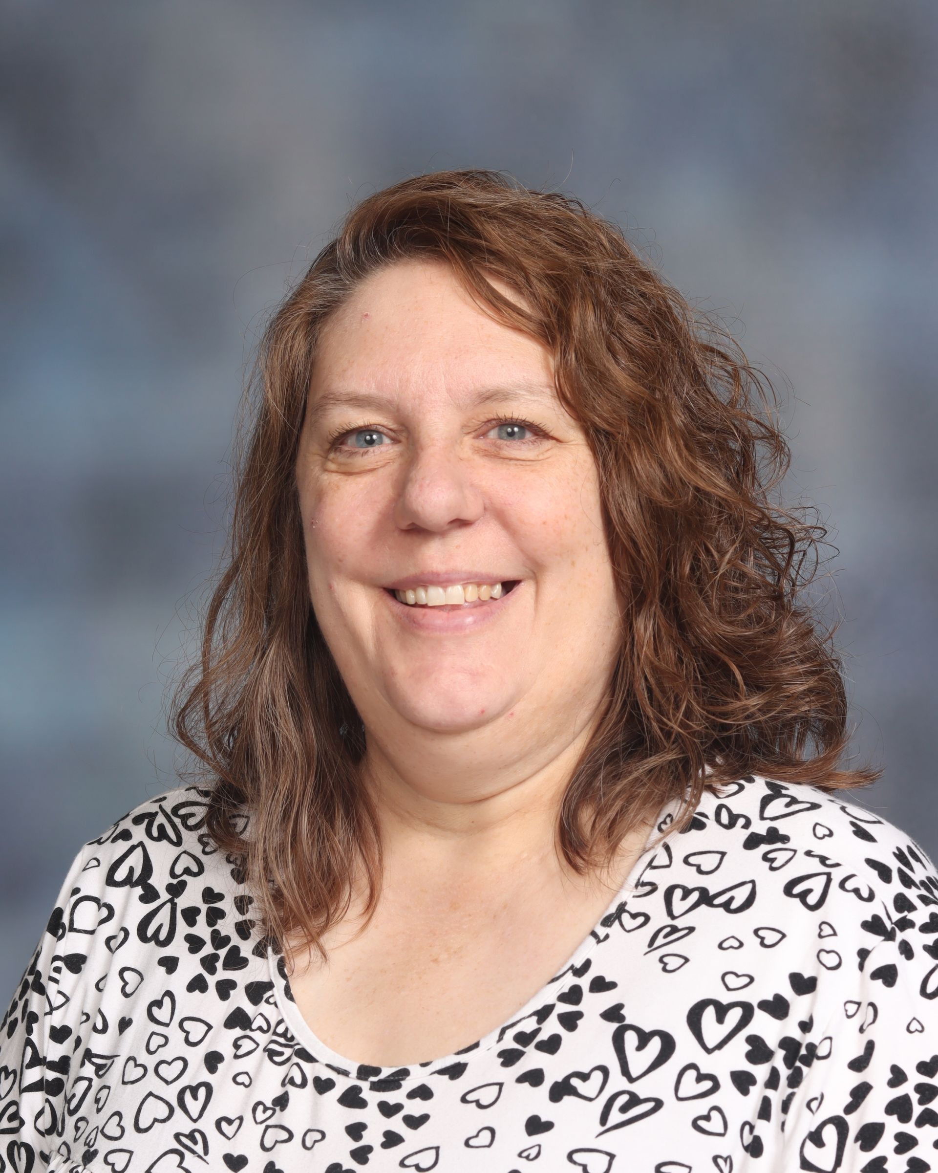A woman wearing glasses and a blue shirt that says `` i became a school teacher '' is smiling for the camera.