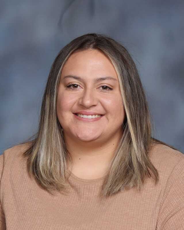 A woman is smiling for a picture in front of a blue background.