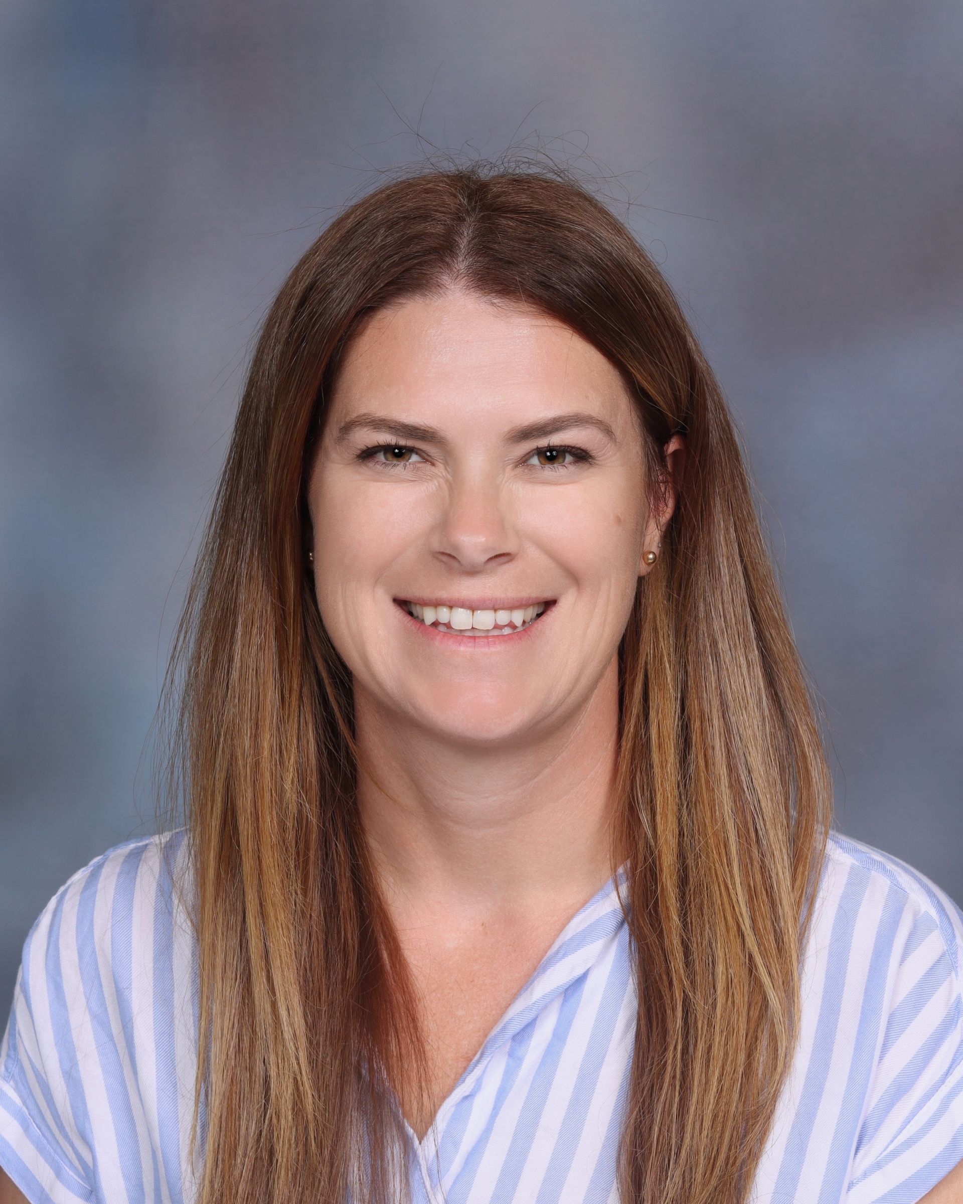 A woman with long brown hair is smiling for a picture.