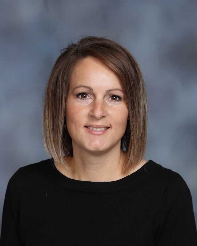 The woman is wearing a black shirt and smiling for the camera.