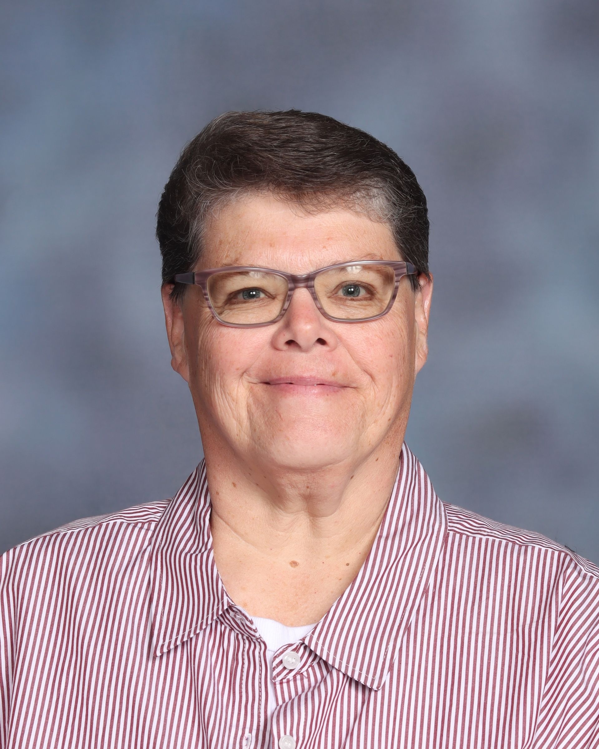 A man wearing glasses and a blue shirt is smiling for the camera.