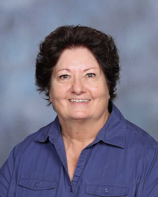 A woman in a blue shirt is smiling for the camera.
