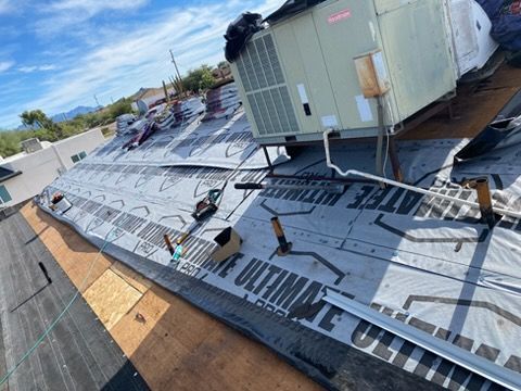 Roof under construction with HVAC unit, featuring black underlayment and plywood.