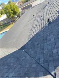 Roofers working on a residential roof under a bright sunny sky.