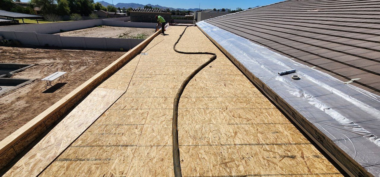 Rooftop construction with OSB boards, a worker, and a drainage system.