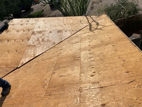 Plywood roof with visible seams and fasteners, outdoors. A person's legs are visible at the bottom left.