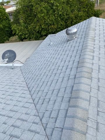 Gray asphalt shingle roof with a vent and satellite dish, viewed from above.