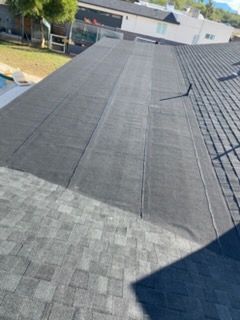 A roof with a combination of dark gray shingles and a flat, black membrane.