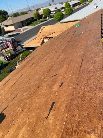 View from a roof of a house under construction. Brown plywood is exposed; truck visible in the distance.