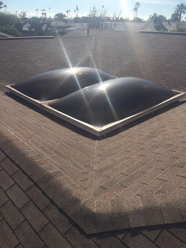 Dome skylights on a brown shingle roof, sun shining.