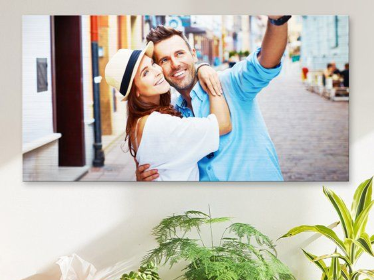 Un couple prend un selfie dans une rue européenne, s'enlaçant et souriant. L'homme en chemise bleue tient son téléphone, la femme en blanc.