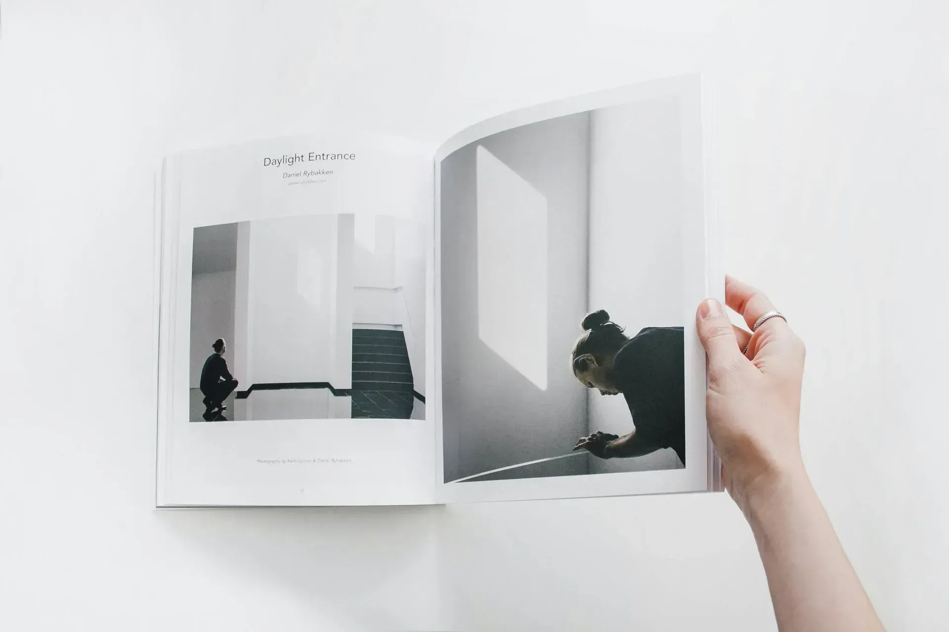 Open book, black and white photographs of a person interacting with an architectural space. Hand holding open book.