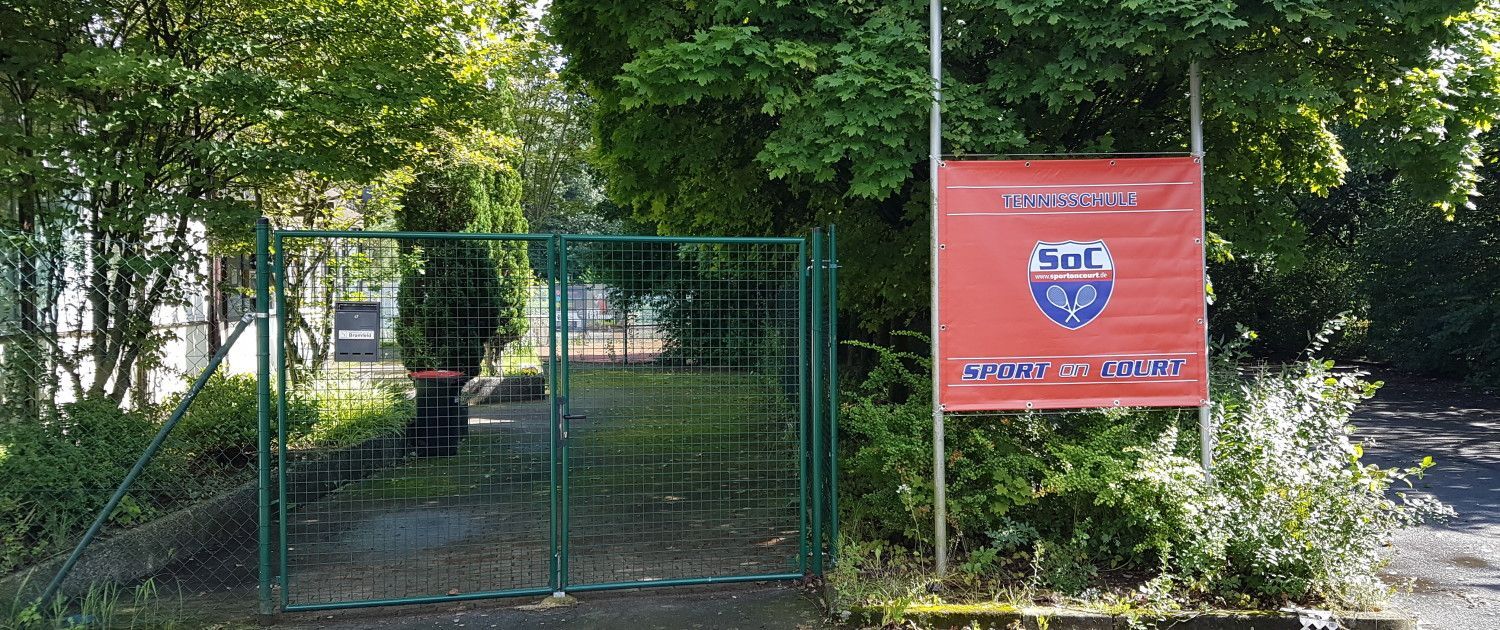 An einer Stange vor einem Zaun hängt ein rotes Schild.