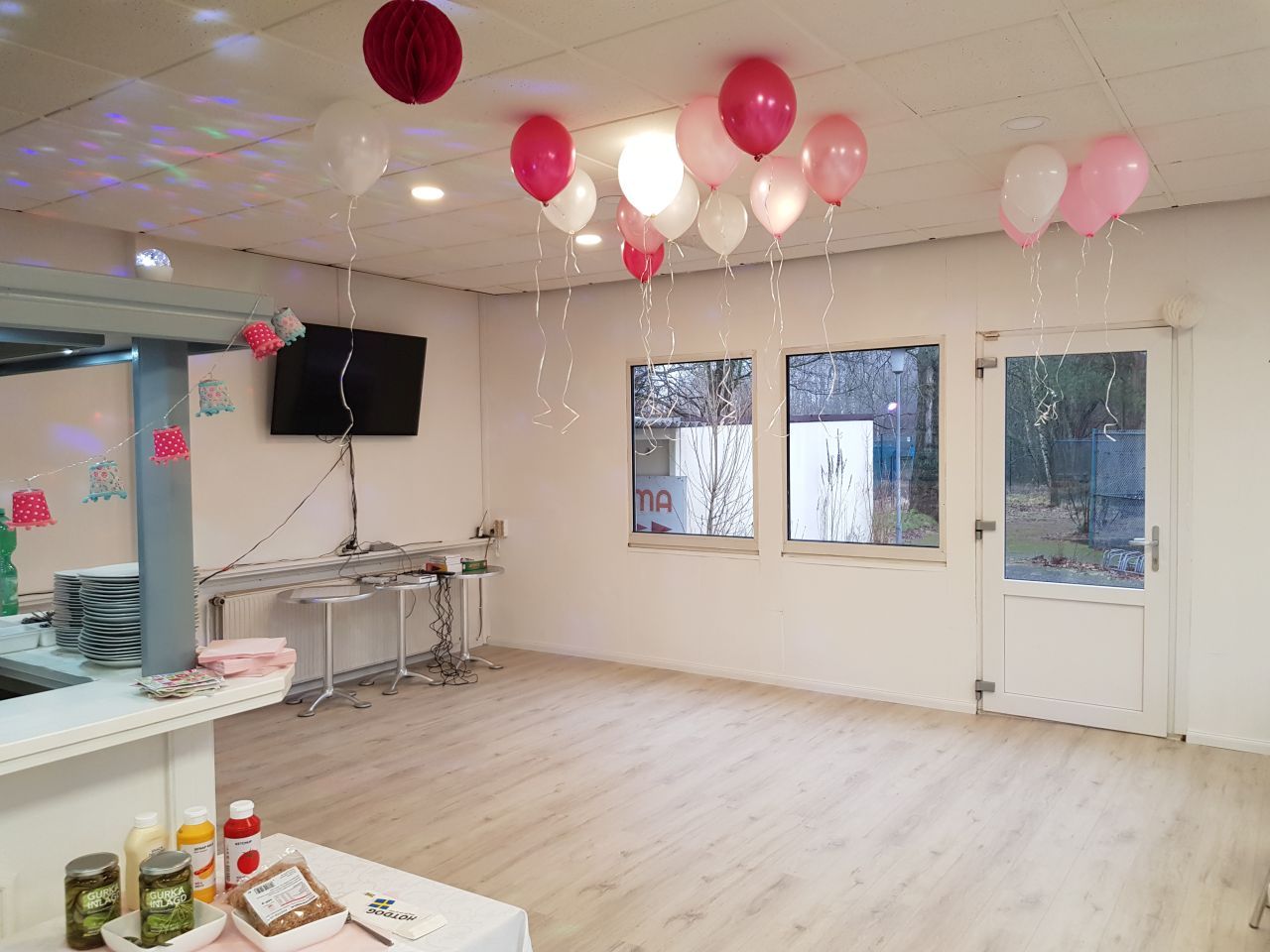 Ein Raum mit von der Decke hängenden Luftballons und einem Fernseher.