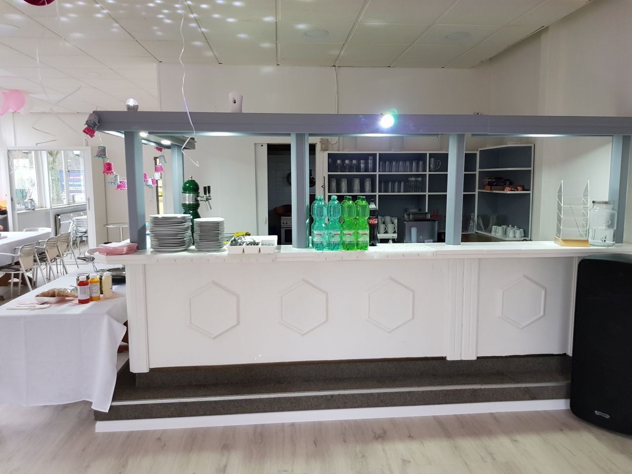 Eine große weiße Bar in einem Raum mit Tischen und Stühlen