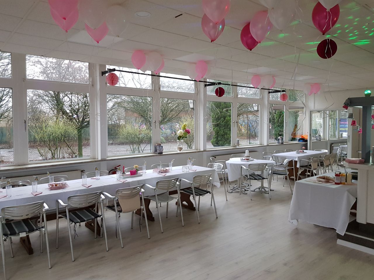 Ein großer Raum mit Tischen und Stühlen und Luftballons, die von der Decke hängen.