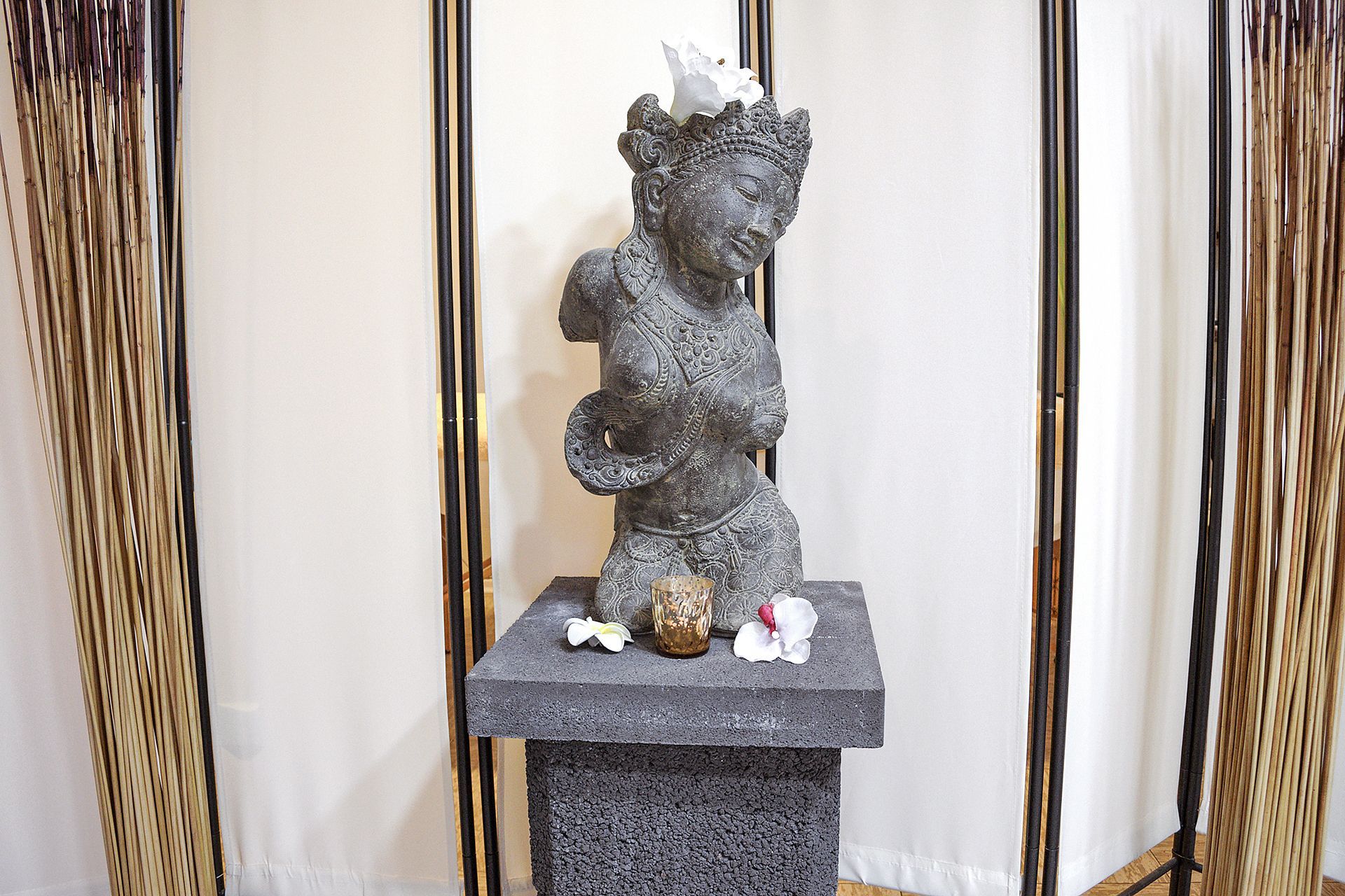 Auf einem Steinsockel sitzt eine Frauenstatue.