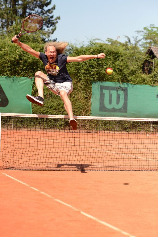 Ein Mann springt auf einem Tennisplatz mit einem Tennisschläger in der Hand in die Luft.