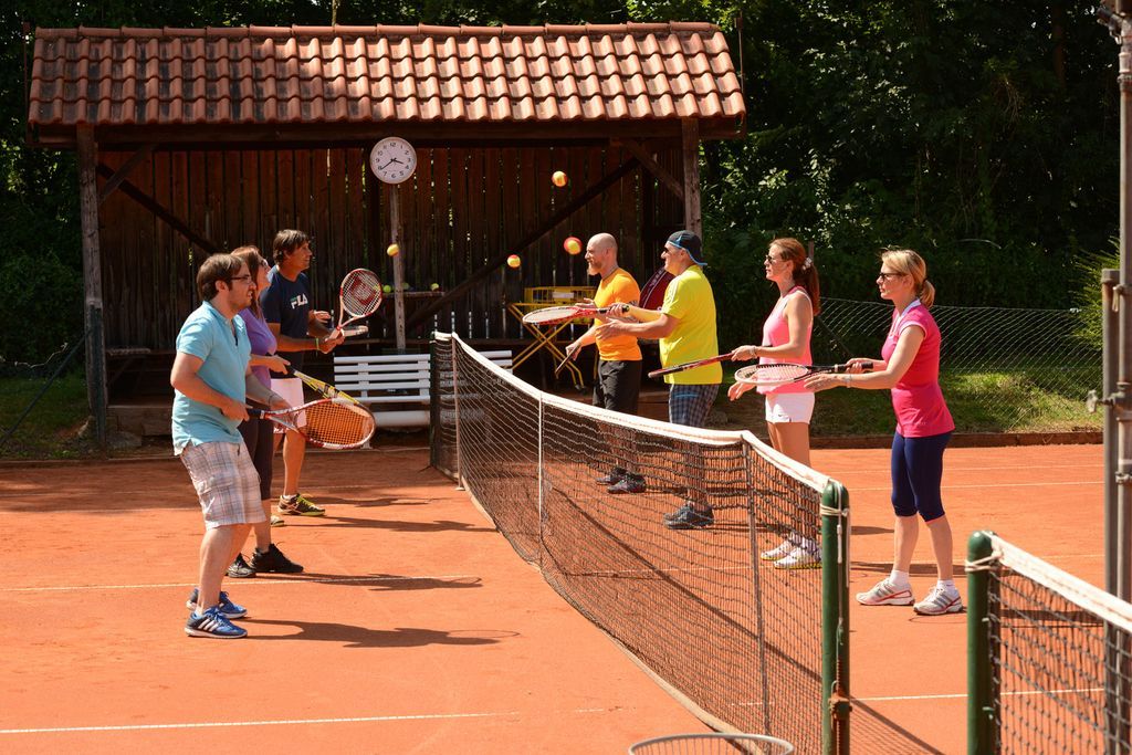 Eine Gruppe von Leuten spielt Tennis auf einem Tennisplatz.