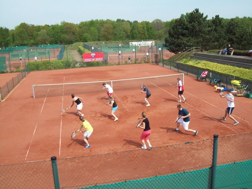 Eine Gruppe von Menschen spielt Tennis auf einem Platz