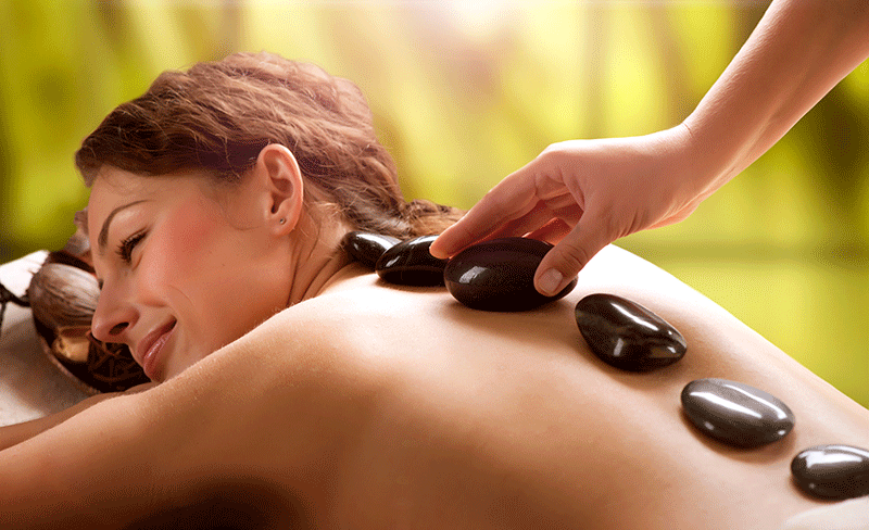 Eine Frau bekommt in einem Spa eine Hot-Stone-Massage.