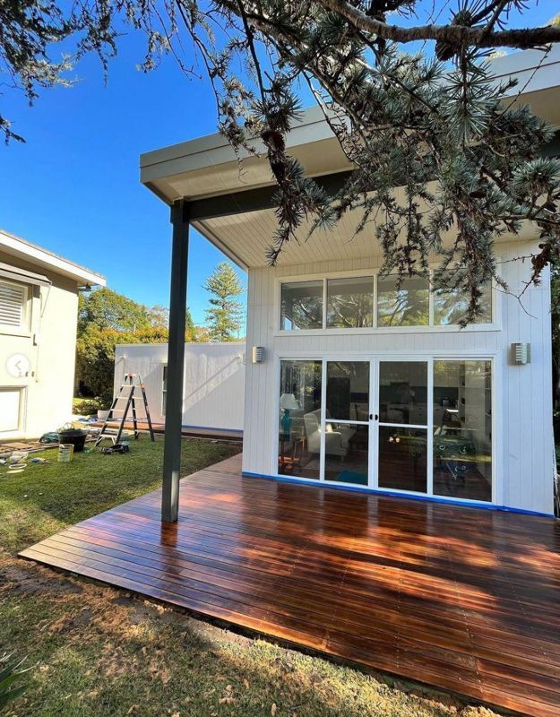 A white house with a wooden deck in front of it.