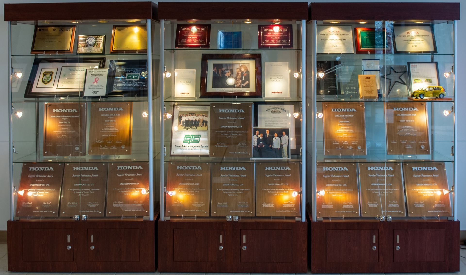 Three glass display cabinets filled with awards and plaques.