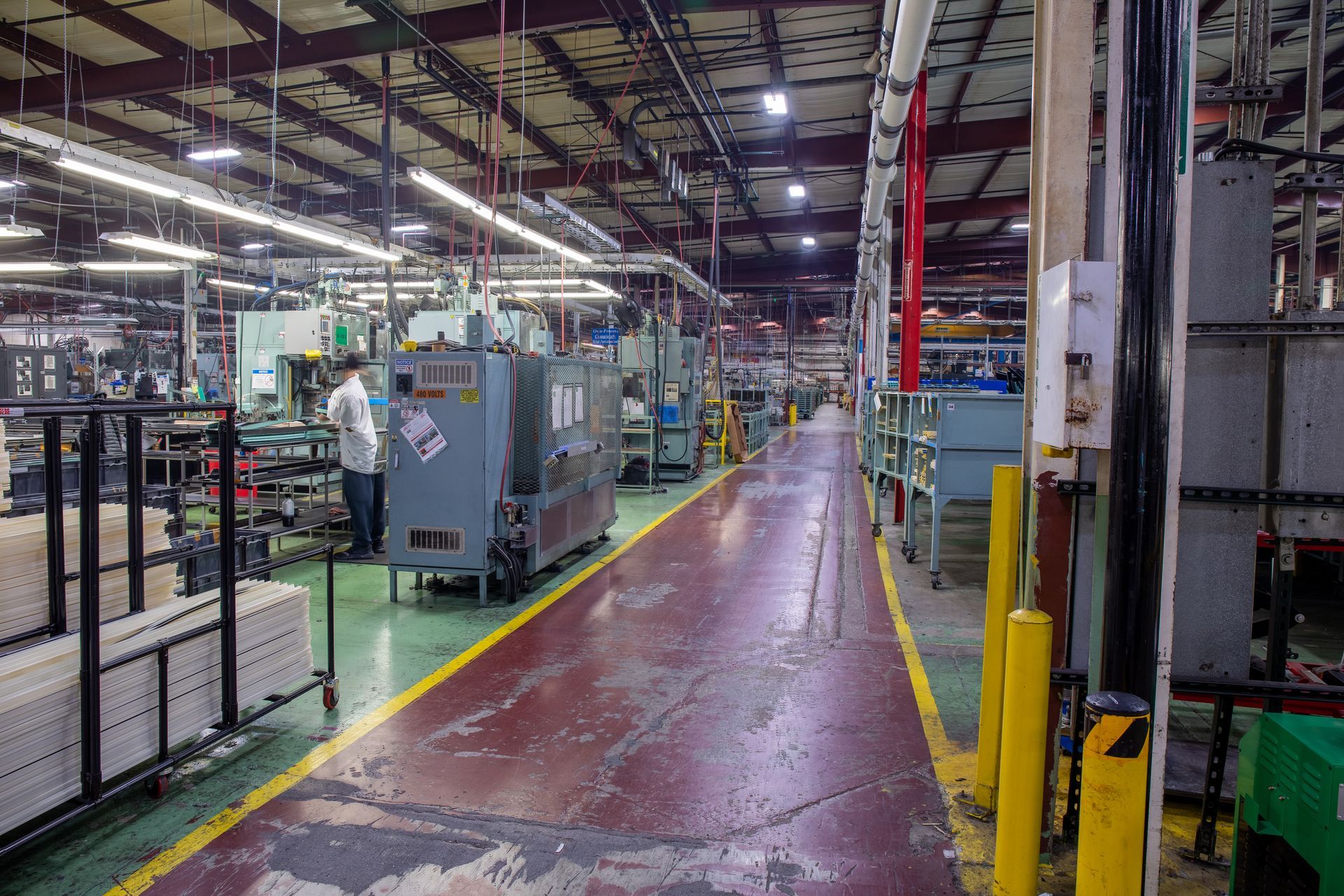 Factory interior with machinery, a worker, and a red and gray floor.