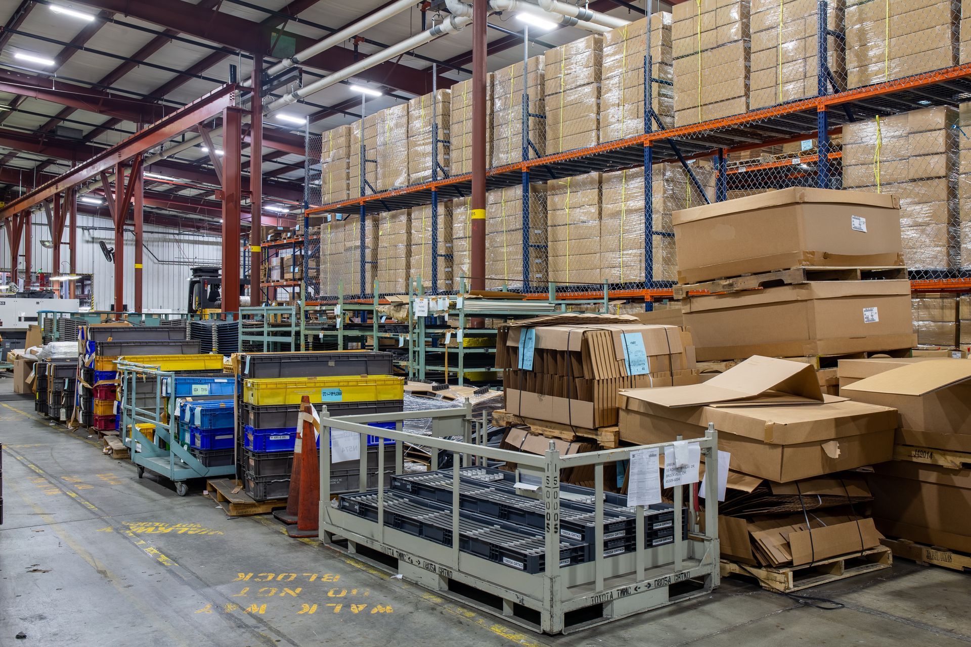 Warehouse interior with shelves of boxes and work carts on the floor.