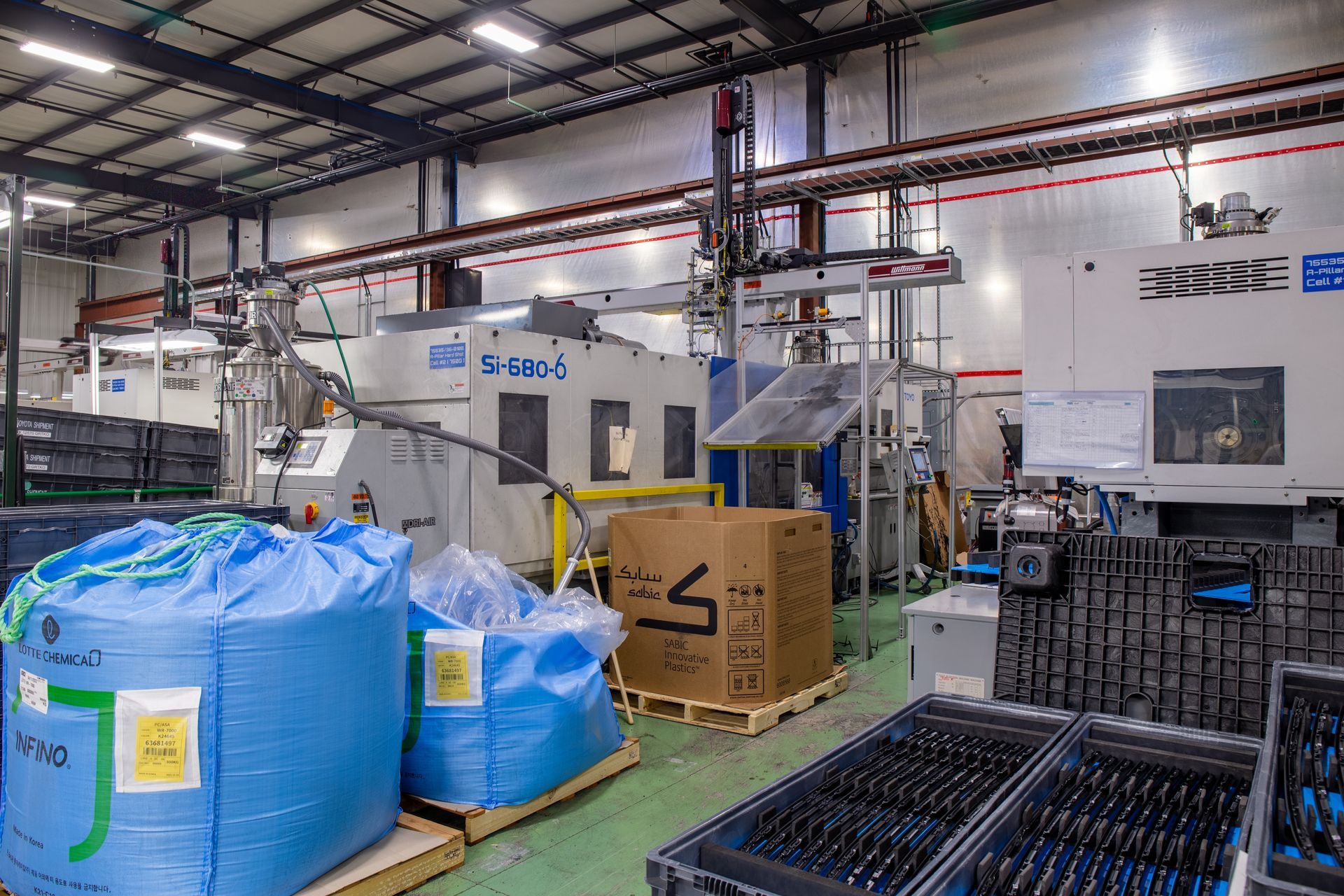 Industrial interior with machinery, blue bags, boxes, and trays of parts.