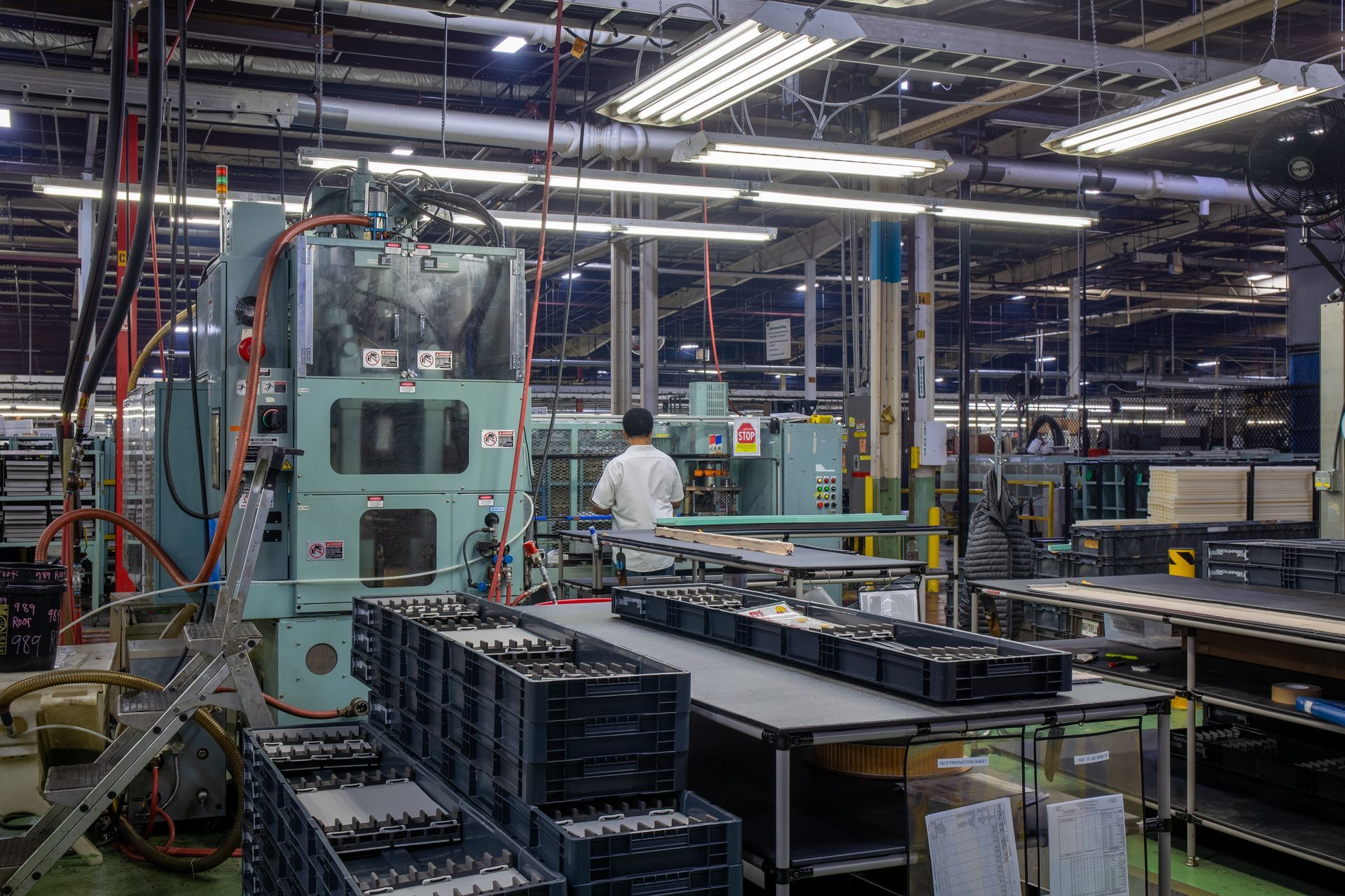 Factory interior with industrial machinery and a worker. Production line with multiple objects in a warehouse-like setting.