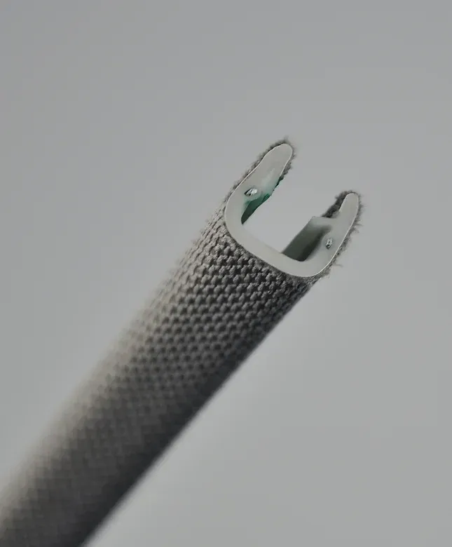 Close-up of a medical instrument tip with two prongs; covered in a textured, gray fabric.