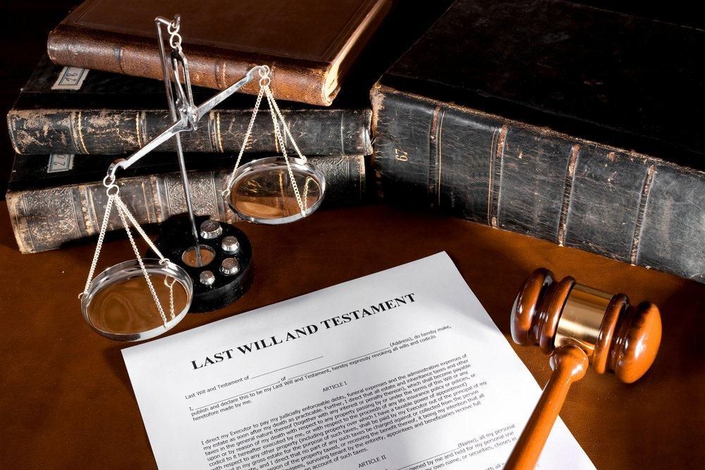 A last will and testament is on a table next to a gavel and scales of justice