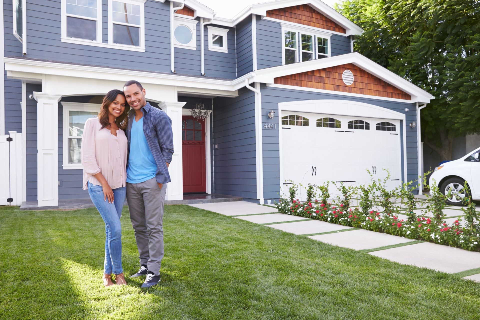 A man and woman are standing in front of their new home.