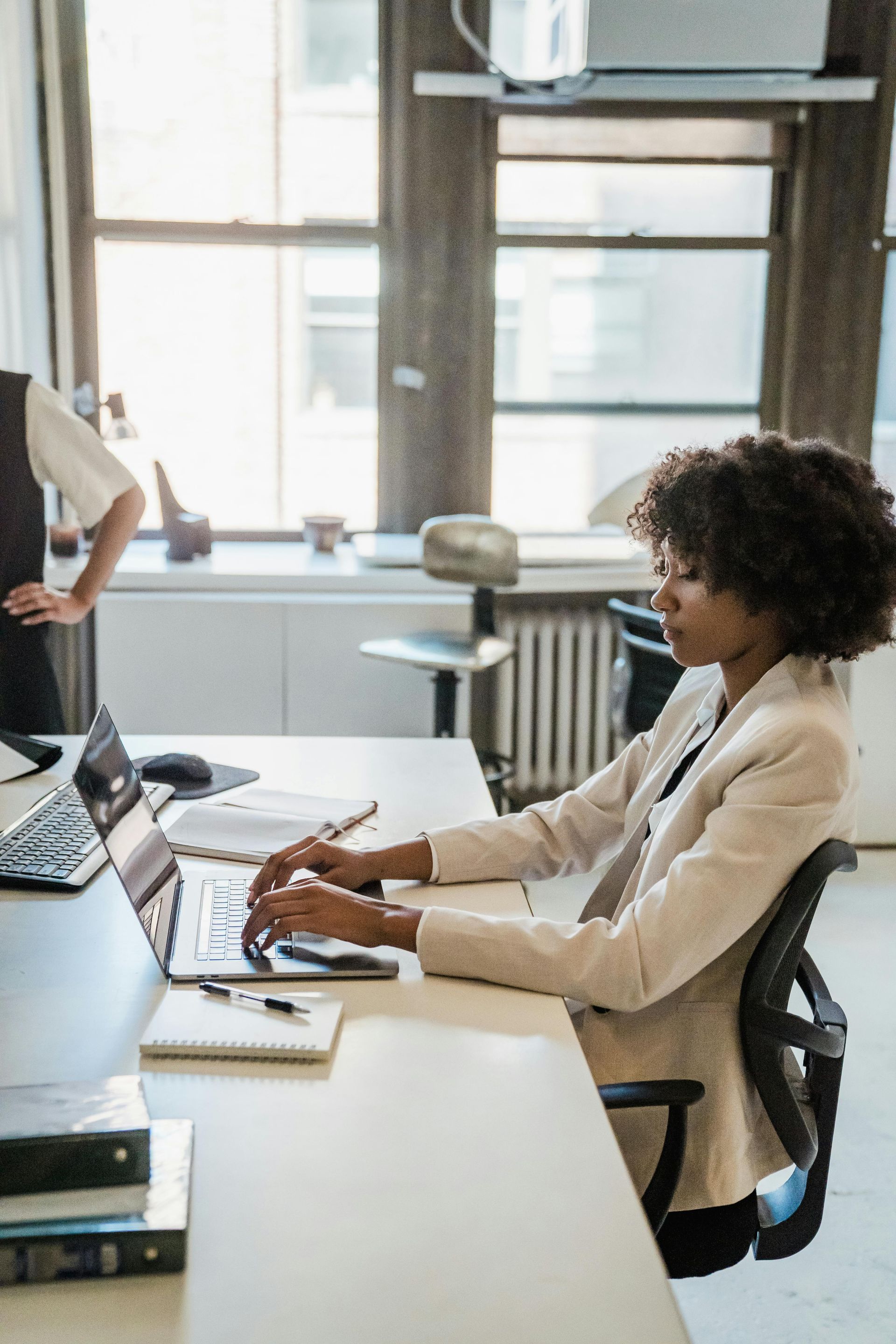 A woman is sitting at a desk using a laptop computer.