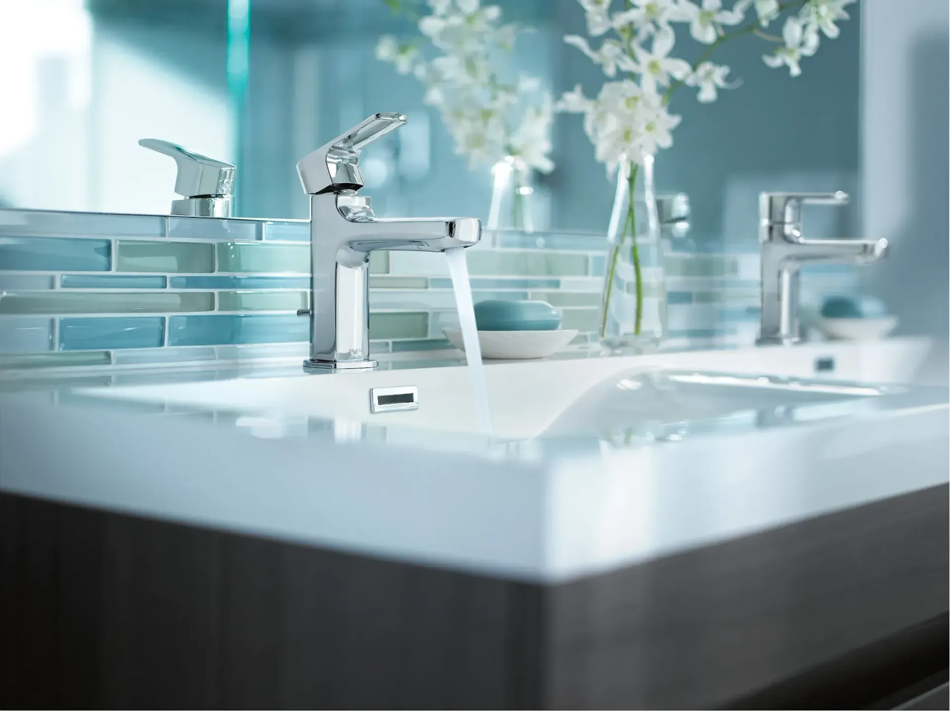 Modern white bathroom with chrome faucets, mirrored backsplash, and soft blue decor