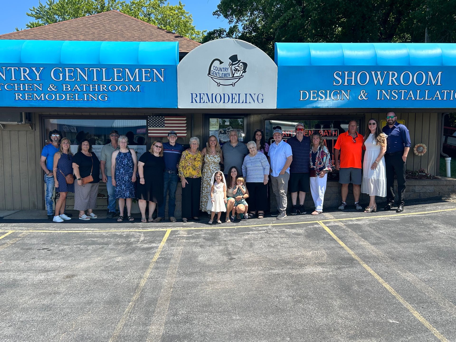 Group posed outside a storefront with blue awning reading “Recycling” and “Showroom & Installation”