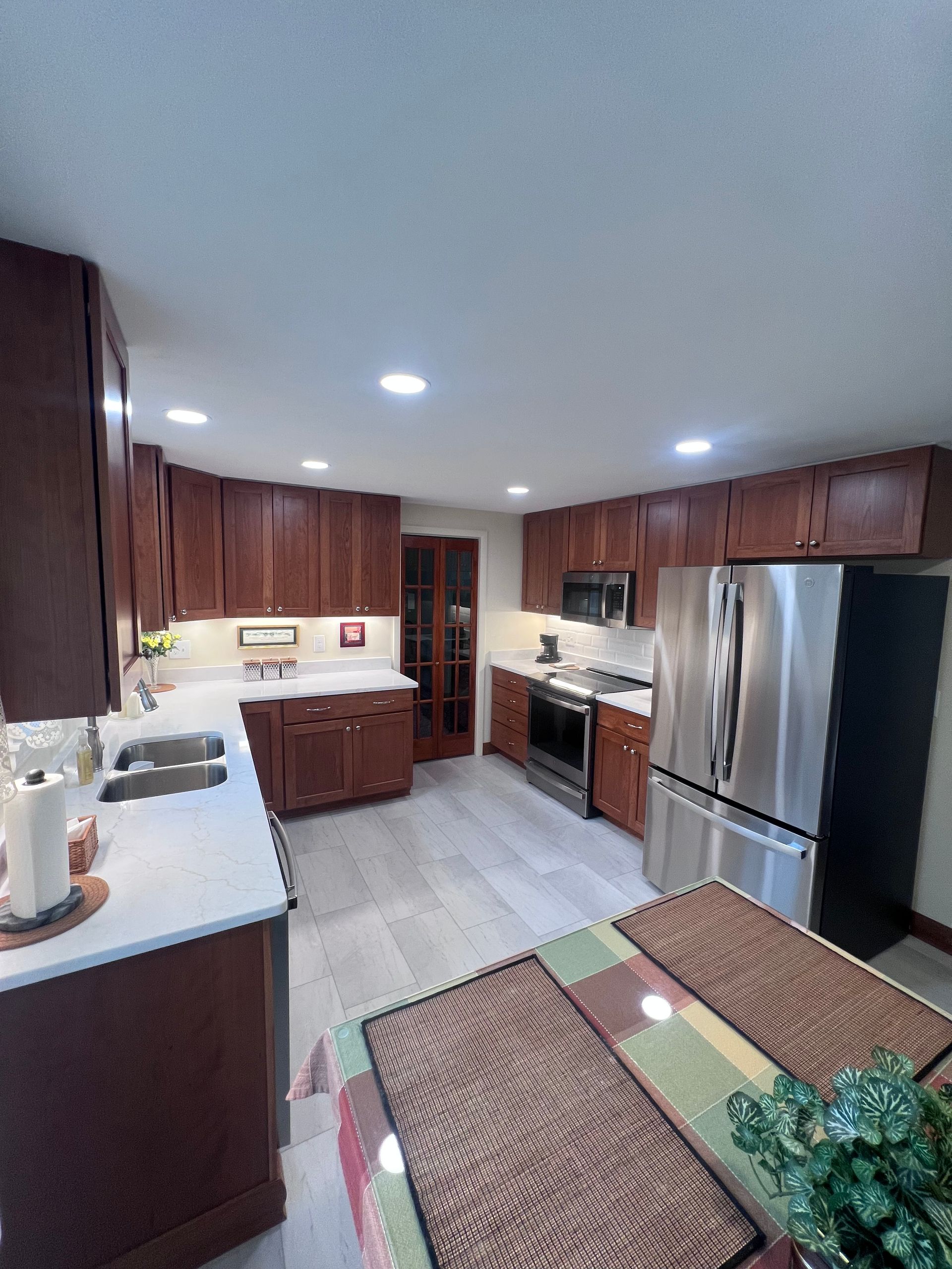 Modern kitchen with dark wood cabinets, stainless steel fridge, and white countertops