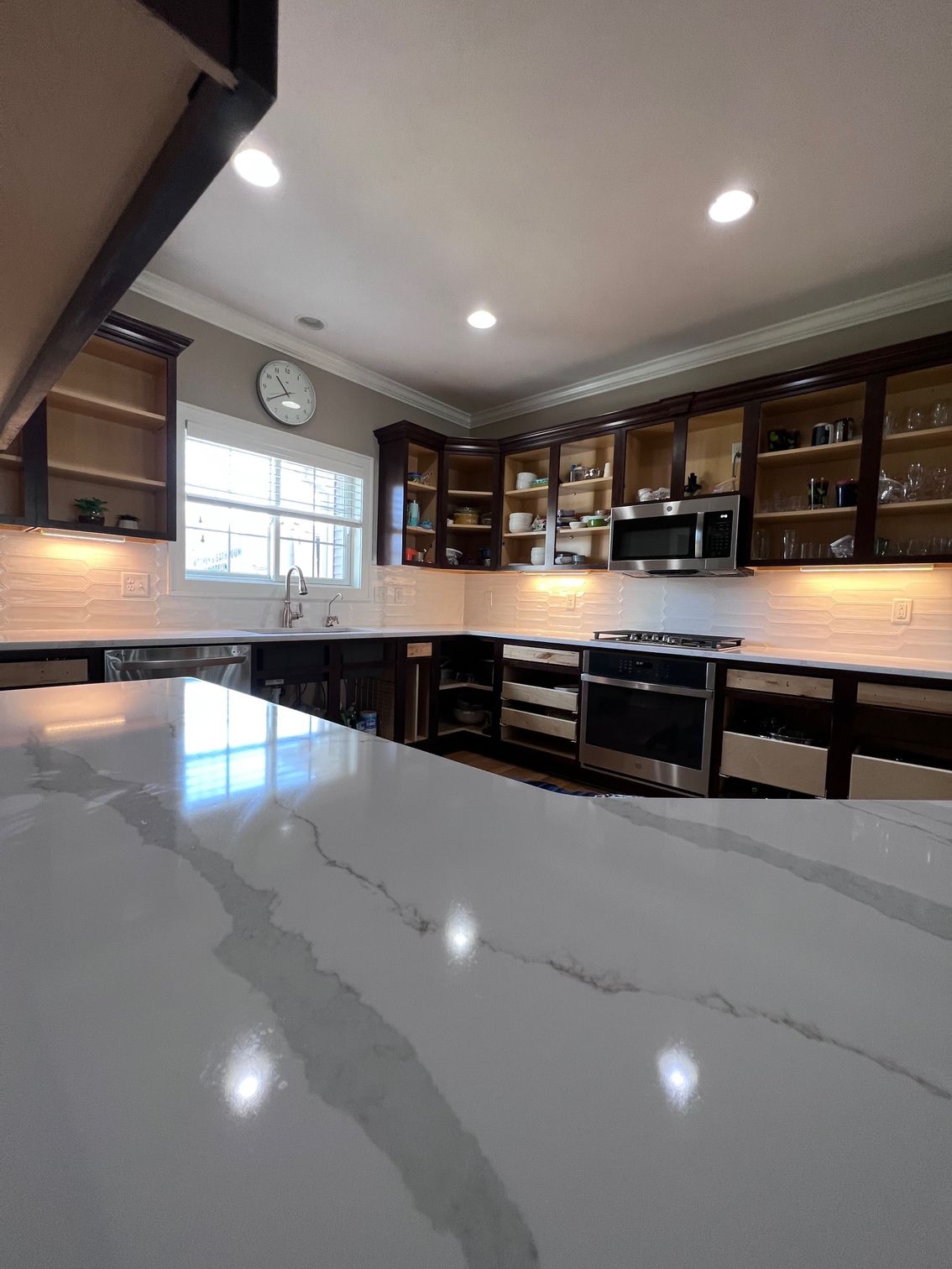 Modern kitchen with marble island, dark wood cabinets, stainless appliances, and bright recessed lighting