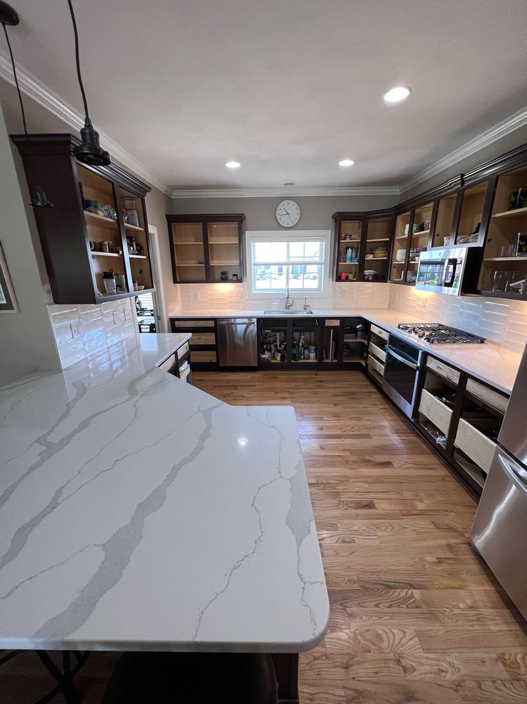 Bright kitchen with white marble island, wood cabinets, and window over the sink
