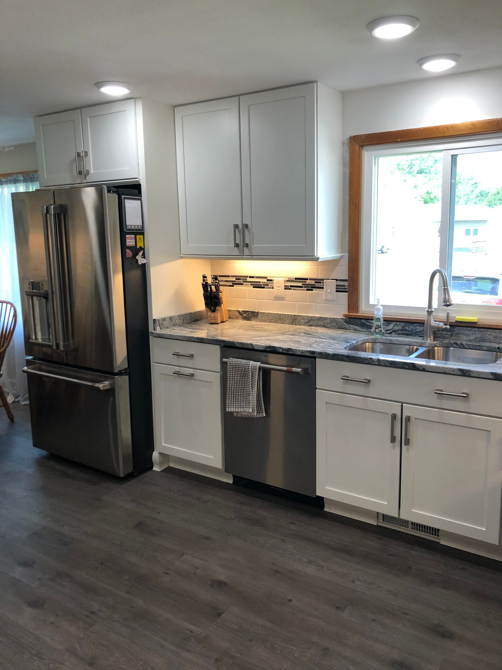 Modern kitchen with stainless steel appliances, gray cabinets, and dark wood flooring