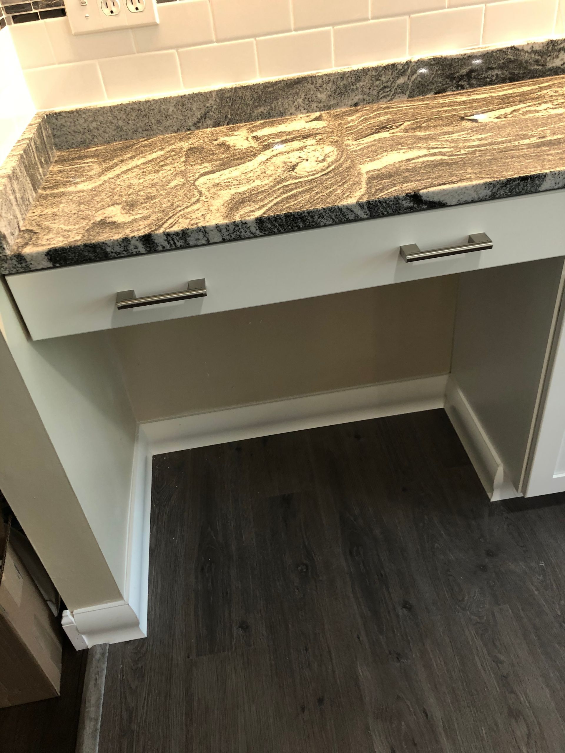 Bathroom vanity with white cabinets, granite countertop, and open space below.