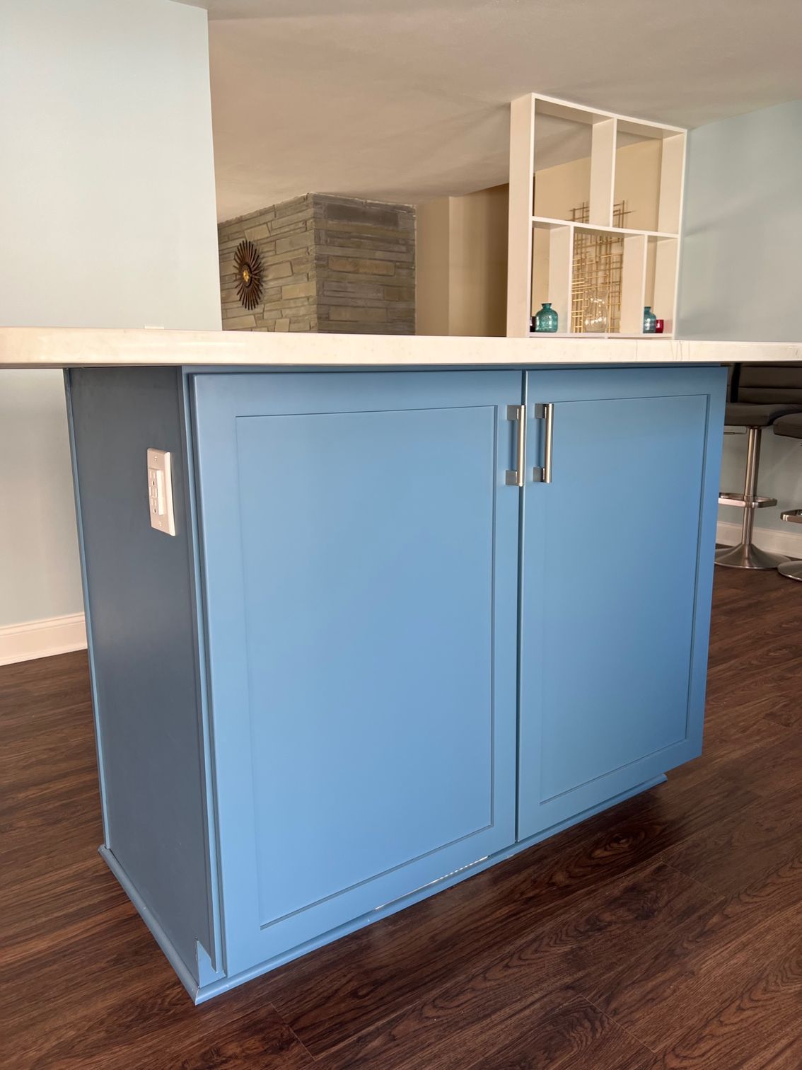 Blue kitchen island cabinet in a modern home interior with dark wood flooring