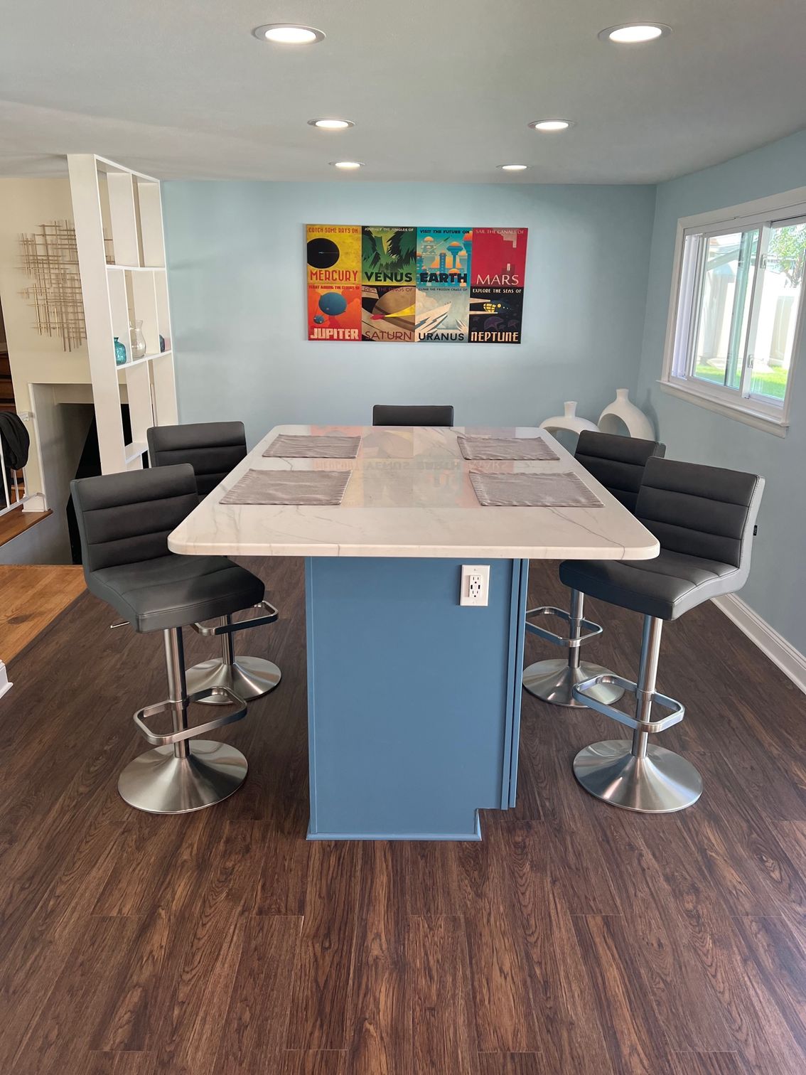 Modern kitchen with a large island, four barstools, and a colorful wall art piece.